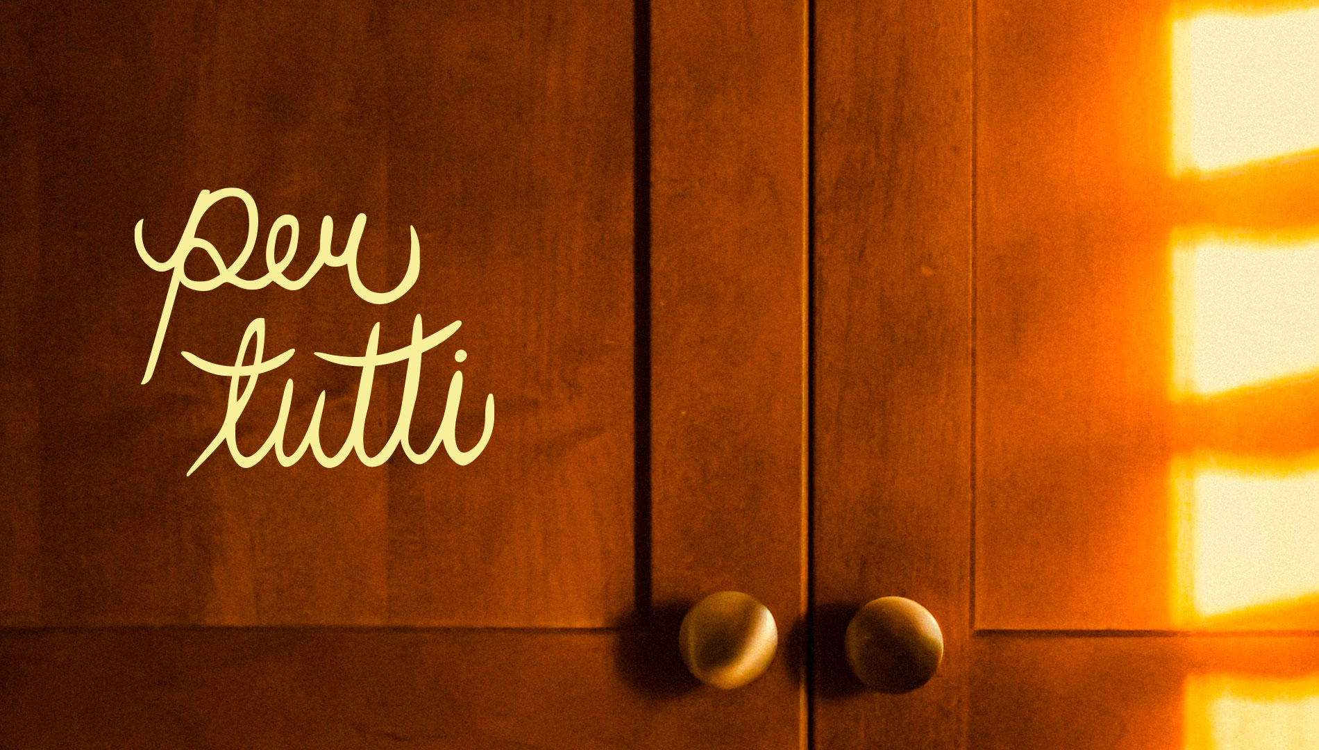 handwritten logo that says per tutti on a kitchen cupboard background